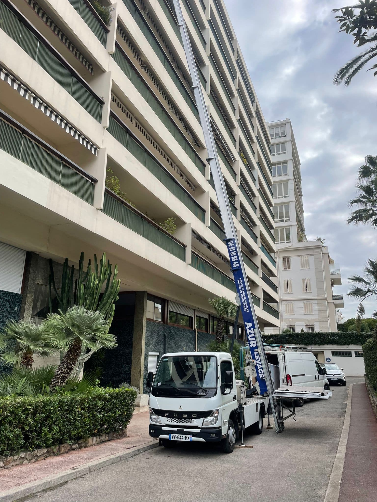 Monte-meuble devant un immeuble bordé de palmiers à Antibes